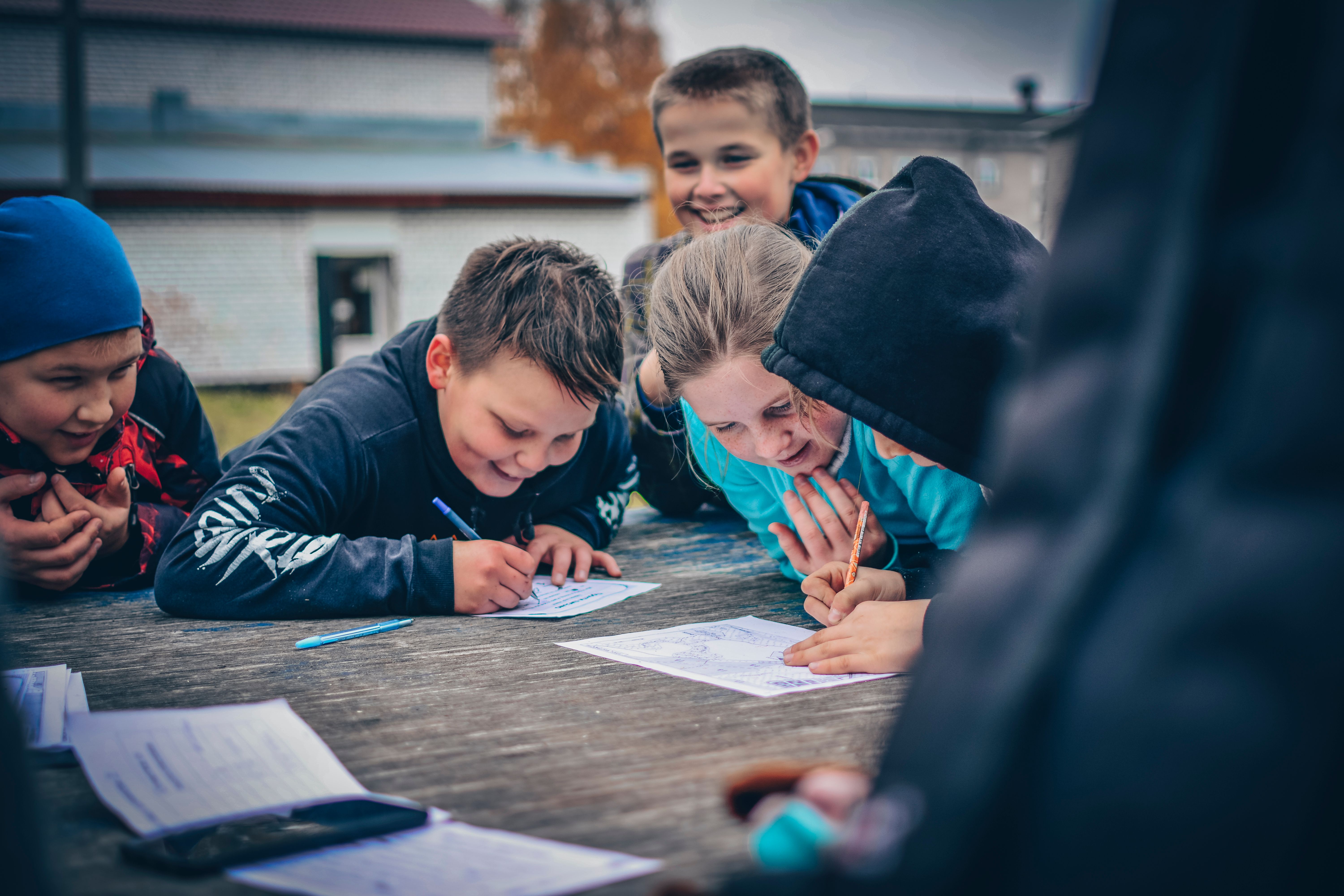 A group of kids gathered around a table drawing together